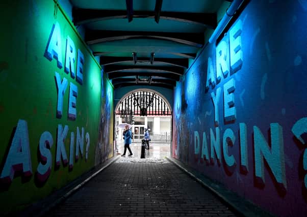 Members of the public walk past graffiti in Glasgow. East Dunbartonshire and Renfrewshire have joined Glasgow city, West Dunbartonshire and East Renfrewshire, with  people banned from visiting other households. Picture: Photo by Jeff J Mitchell/Getty Images