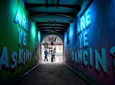 Members of the public walk past graffiti in Glasgow. East Dunbartonshire and Renfrewshire have joined Glasgow city, West Dunbartonshire and East Renfrewshire, with  people banned from visiting other households. Picture: Photo by Jeff J Mitchell/Getty Images