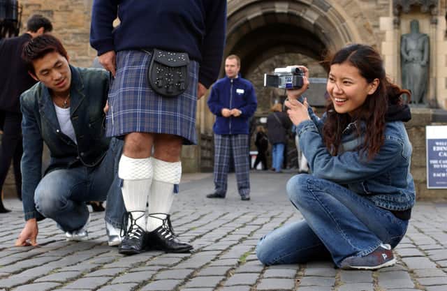 Tourists investigate a kilt at Edinburgh Castle in the days before Covid
