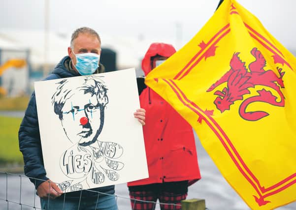 Demonstrators gather to greet Boris Johnson as he visits Stromness, in a week that marked his first year as Prime Minister. Picture: Robert Perry/Getty
