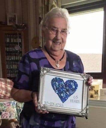 Margaret Davidson holding a blue heart to represent their sapphire anniversary