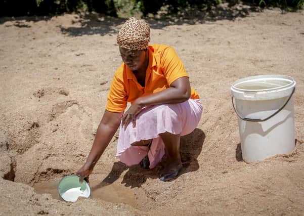 Cecilia drawing water from a shallow well where she waited for hours to fill up her 20 litre bucket.