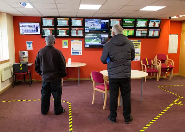 CHAPELHALL, SCOTLAND - JULY 22:  Men watch the TV screens at the Scotbet Independent bookmakers shop, as coronavirus measures are relaxed to allow televisions and seating inside betting shops on July 22, 2020 in Chapelhall, Scotland. Independent Bookmakers are concerned that they will put out of business through a lack of help from the Scottish government during the Coronavirus pandemic. The Betting and Gaming Council (BGC) has called for Scotland to follow the lead of the UK Government and make betting shops eligible for rates relief. (Photo by Robert Perry/Getty Images)