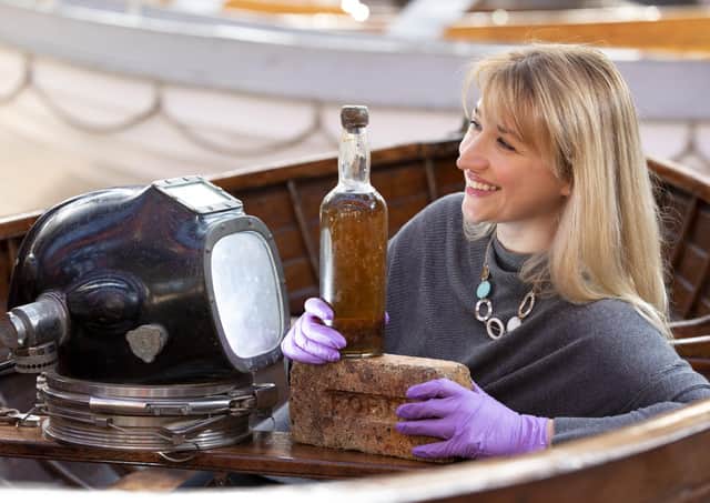 Abigail McIntyre, Senior Curator at the Scottish Maritime Museum, pictured with an eighty year old bottle of Scottish whisky salvaged from the 1923 SS Politician