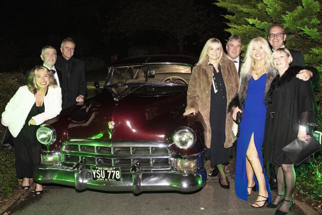 Event sponsor Brandabble team on arrival pose by a 1949 Cadillac Coupe De Ville
