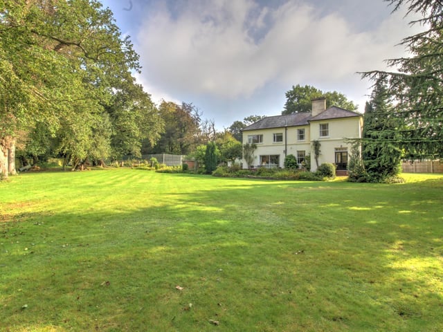 The remainder of the grounds are laid to lawn with mature trees and hedgerow, along with a raised side patio terrace which is on the west side of the property.