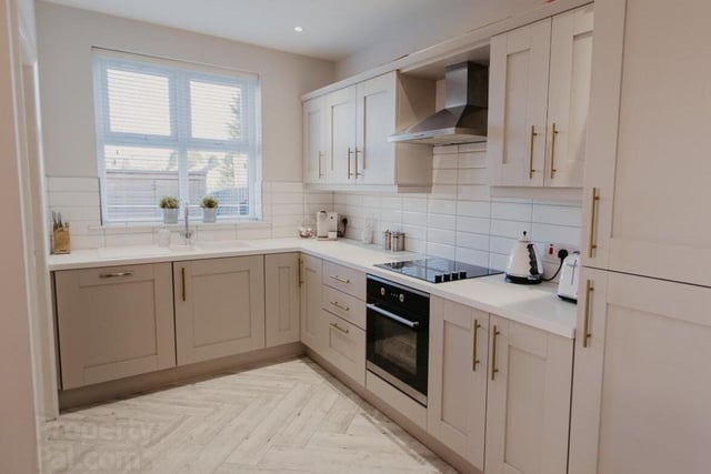 The kitchen has a range of built-in appliances and is fitted with high and low units in modern neutral tones.