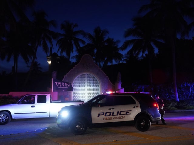 A supporter of former President Donald Trump drives past his Mar-a-Lago estate, Monday, Many had gathered to protest the raid.