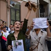 Nasibe Samsaei, an Iranian woman living in Turkey, holds up her ponytail after cutting it off during a protest outside the Iranian consulate in Istanbul (Picture: Yasin Akgul/AFP via Getty Images)