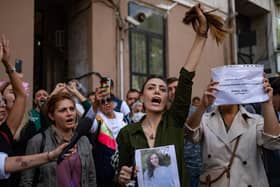 Nasibe Samsaei, an Iranian woman living in Turkey, holds up her ponytail after cutting it off during a protest outside the Iranian consulate in Istanbul (Picture: Yasin Akgul/AFP via Getty Images)