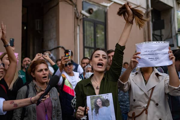 Nasibe Samsaei, an Iranian woman living in Turkey, holds up her ponytail after cutting it off during a protest outside the Iranian consulate in Istanbul (Picture: Yasin Akgul/AFP via Getty Images)