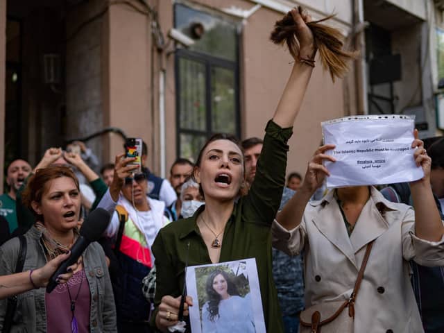 Nasibe Samsaei, an Iranian woman living in Turkey, holds up her ponytail after cutting it off during a protest outside the Iranian consulate in Istanbul (Picture: Yasin Akgul/AFP via Getty Images)
