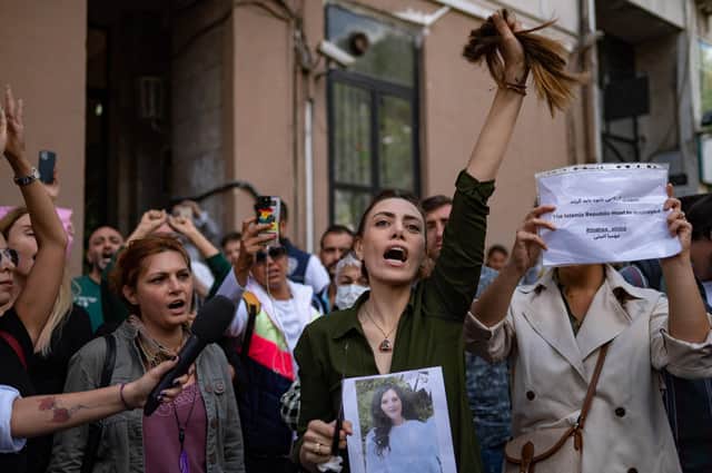 Nasibe Samsaei, an Iranian woman living in Turkey, holds up her ponytail after cutting it off during a protest outside the Iranian consulate in Istanbul (Picture: Yasin Akgul/AFP via Getty Images)