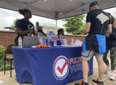 People visit a booth set up by Fulton County to recruit new poll workers at the Alpharetta Farmers Market on Sept. 10, 2022, in Alpharetta, Ga. Lies about the integrity of the 2020 presidential contest by former President Donald Trump and his allies are spurring new interest in working the polls in Georgia and elsewhere in the nation for the upcoming midterm elections. (AP Photo/Sudhin Thanawala)