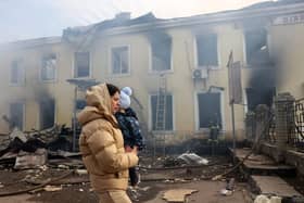 TOPSHOT - A local resident and her child walks past the railway station destroyed by a Russian missile attack in Kostyantynivka, Donetsk region.