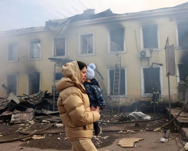 TOPSHOT - A local resident and her child walks past the railway station destroyed by a Russian missile attack in Kostyantynivka, Donetsk region.