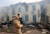 TOPSHOT - A local resident and her child walks past the railway station destroyed by a Russian missile attack in Kostyantynivka, Donetsk region.