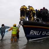 People are helped ashore from an RNLI lifeboat on a beach at Dungeness, south-east England, after being rescued while crossing the English Channel (Picture: Ben Stansall/AFP via Getty Images)