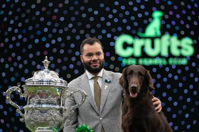 Baxer the Flat-Coated Retriever with handler Patrick Oware after winning Best in Show during the final day of the Crufts Dog Show at the Birmingham National Exhibition Centre (NEC). Picture date: Sunday March 13, 2022. PA Photo. Joe Giddens/PA Wire