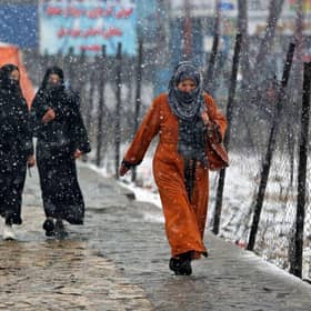 Commuters make their way along a street during snowfall in Kabul on Thursday.