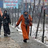 Commuters make their way along a street during snowfall in Kabul on Thursday.