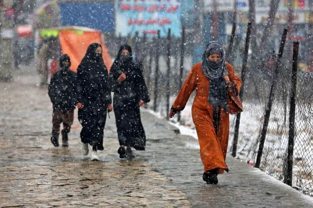 Commuters make their way along a street during snowfall in Kabul on Thursday.
