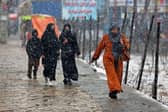 Commuters make their way along a street during snowfall in Kabul on Thursday.