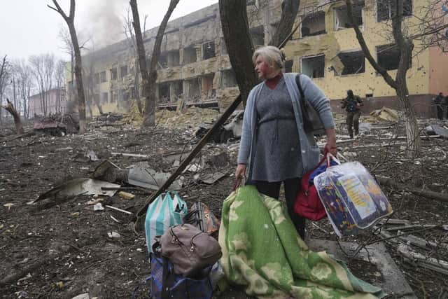 A woman walks outside the damaged by shelling maternity hospital in Mariupol, Ukraine