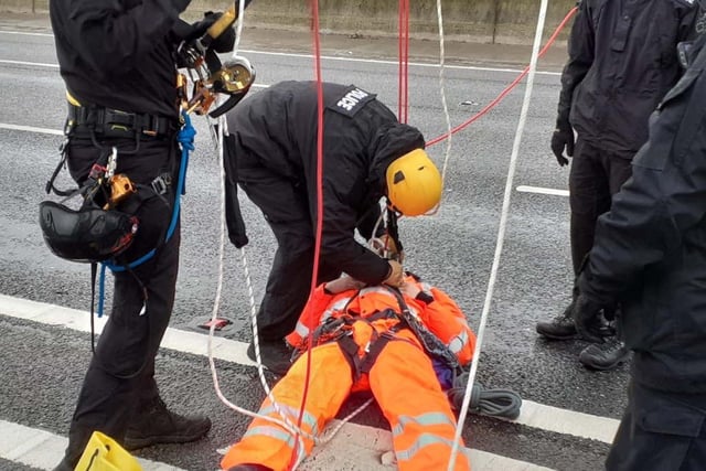 A Just Stop Oil protester being detained after they climbed a gantry on the M25, leading to the closure of the motorway. Picture date: Monday November 7, 2022.