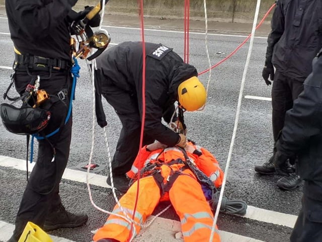 A Just Stop Oil protester being detained after they climbed a gantry on the M25, leading to the closure of the motorway. Picture date: Monday November 7, 2022.