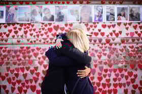 People hugging at the National Covid Memorial Wall in London