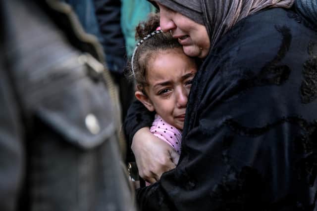 A Palestinian woman holds a child as they mourn relatives killed in an Israeli bombardment in Gaza City last month (Picture: AFP via Getty Images)