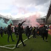 Supporters protest against Manchester United's owners on the Old Trafford pitch, forcing the match against Liverpool to be postponed (Photo by OLI SCARFF/AFP via Getty Images)