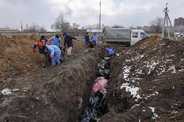 Dead bodies are put into a mass grave on the outskirts of Mariupol, Ukraine, Wednesday, March 9, 2022, as people cannot bury their dead because of the heavy shelling by Russian forces. (AP Photo/Evgeniy Maloletka)