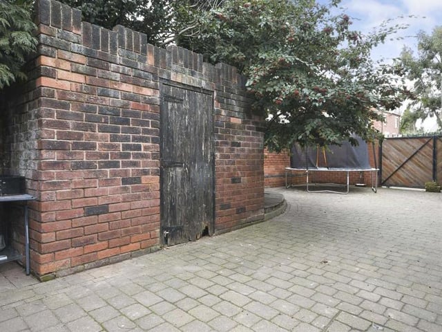 Behind the gates at the side of the property is this outbuilding.  The paved driveway leads to the detached garage.