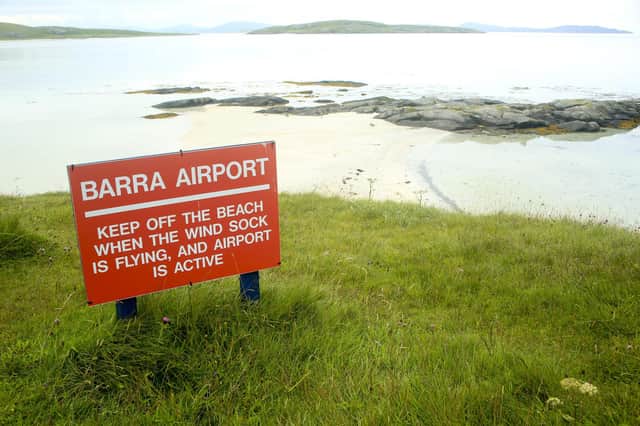A red sign for the Barra Airport which uses the beach for runways. This was taken at high tide and the runways are covered.
