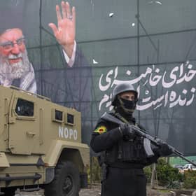police officer stands near an armoured-vehicle and a poster featuring the late Supreme Leader Ali Khamenei in Tehran (Picture: Majid Saeedi/Getty Images)