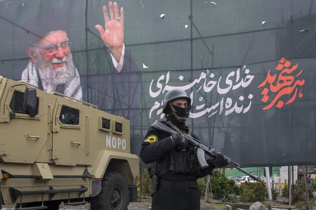 police officer stands near an armoured-vehicle and a poster featuring the late Supreme Leader Ali Khamenei in Tehran (Picture: Majid Saeedi/Getty Images)