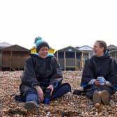 Two friends, wearing coats, have a conversation