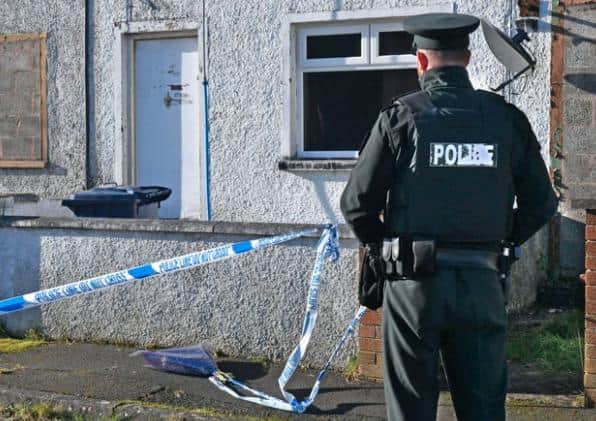 A police officer repositions flowers that were left by sympathisers at the scene of what the PSNI have described as a 'suspicious death'at a house at Carrickdale Gardens off the Tandragee Road in Portadown, County Armagh. Photo Alan Lewis.