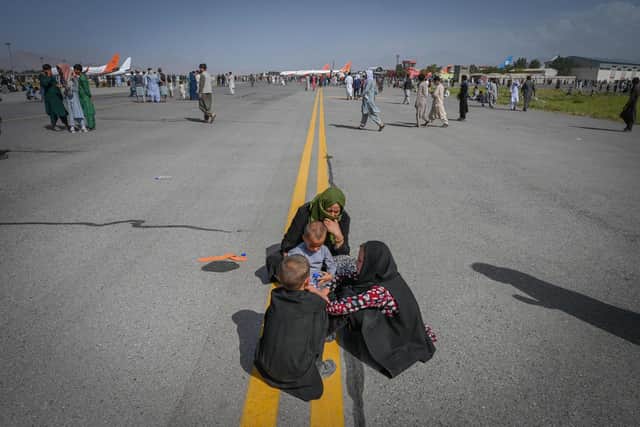 An Afghan family sits on the tarmac at Kabul airport, where thousands of people fled in the hope of escaping the Taliban (Picture: Wakil Kohsar/AFP via Getty Images)