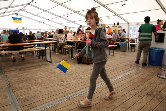 A child refugee from Ukraine holds a Ukrainian flag as she walks through a temporary welcome centre tent outside the main train station in Berlin, Germany, earlier this year. Picture: Getty Images