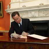 The then Prime Minister David Cameron signing the Book of Commitment ahead of Holocaust Memorial Day 2013, watched by survivor Freda Wineman.