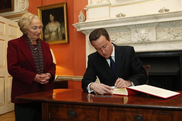 The then Prime Minister David Cameron signing the Book of Commitment ahead of Holocaust Memorial Day 2013, watched by survivor Freda Wineman.