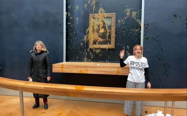 Two environmental activists from the collective dubbed "Riposte Alimentaire" (Food Retaliation) stand in front of Leonardo Da Vinci's "Mona Lisa" painting after hurling soup at the artwork, at the Louvre museum in Paris.