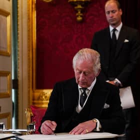 Prince William, Prince of Wales and Camilla, Queen Consort watch as King Charles III signs an oath to uphold the security of the Church in Scotland, during a meeting of the Accession Council inside St James's Palace in London