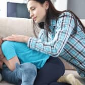 A mother stroking the back and comforting a little girl at home