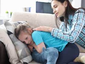 A mother stroking the back and comforting a little girl at home