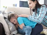 A mother stroking the back and comforting a little girl at home