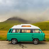 An old green camper van in the shadow of the misty Cuillin mountains and a rainbow, at Glen Brittle on the Isle of Skye, Scotland